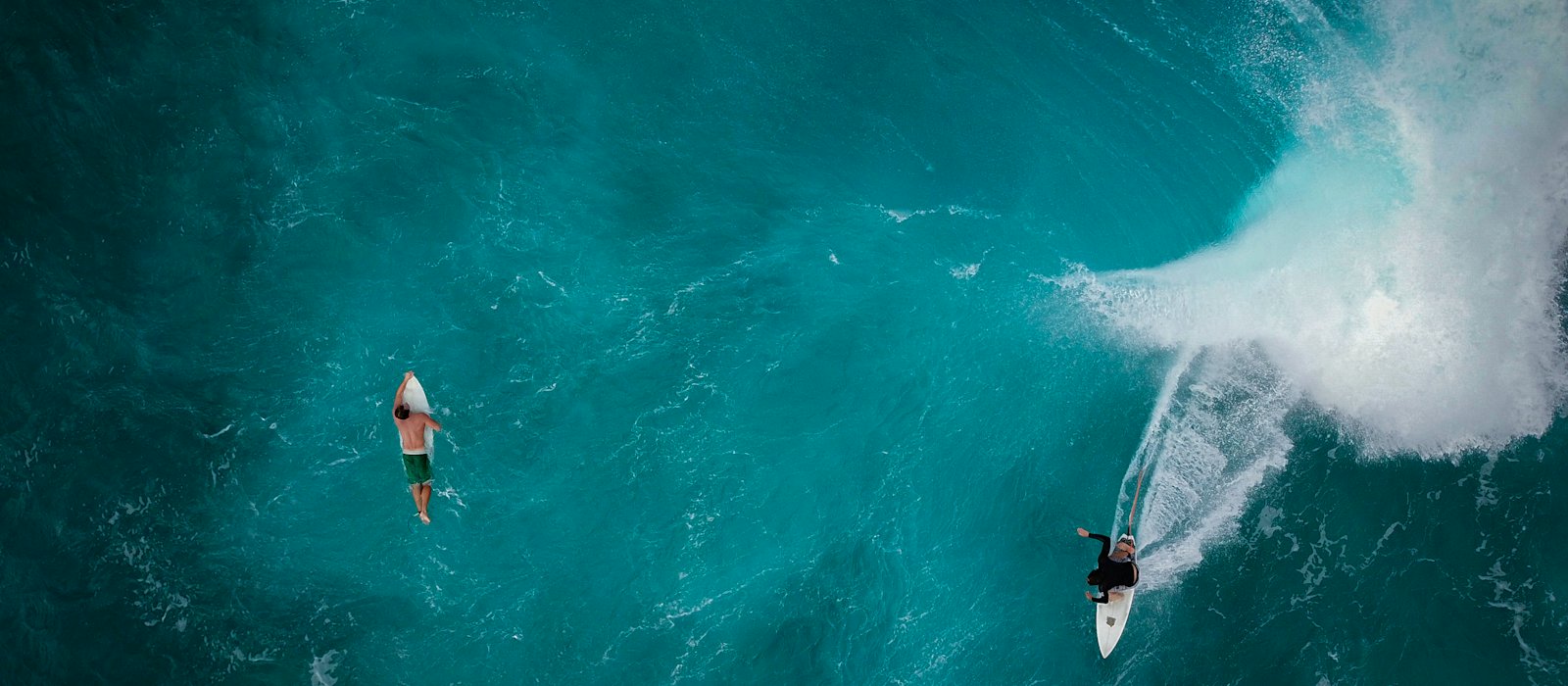 Zwei Surfer an einer brechenden Welle, von oben
